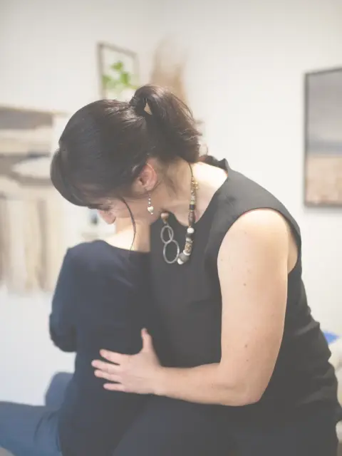Osteopath assessing patient's shoulder mobility during chronic pain consultation